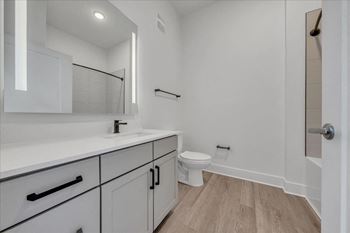 A white bathroom with a toilet, sink, and mirror.